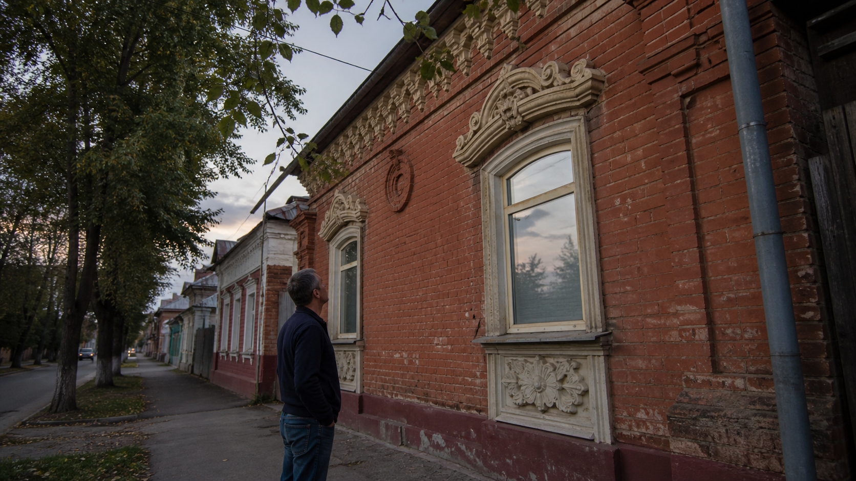 Мужчина во время вечерней прогулки остановился рассмотреть старинное оформление дома