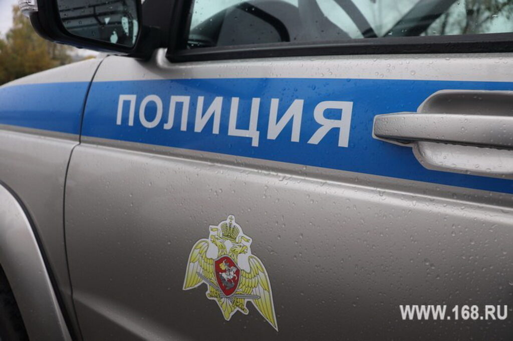 Крупный план мокрой от дождя двери служебного автомобиля с синей полосой, надписью «Полиция» и эмблемой