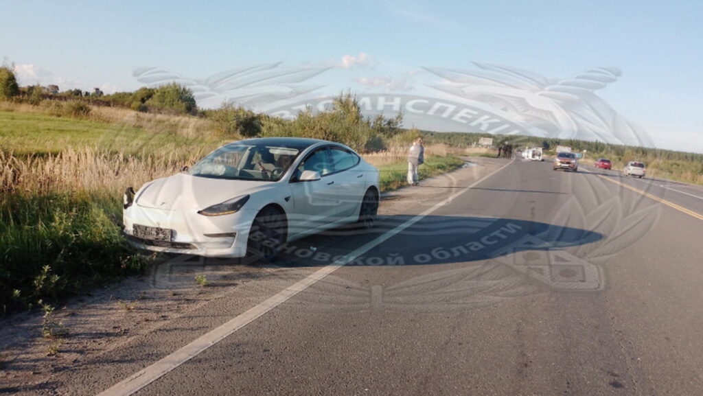 Белый седан с поврежденной передней частью стоит на обочине загородной дороги