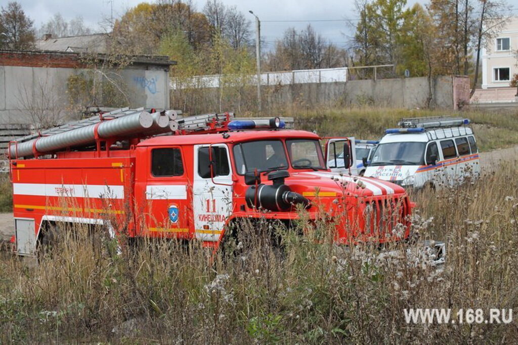 Красная пожарная машина и автомобиль спасательной службы стоят среди высокой сухой травы