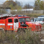 Красная пожарная машина и автомобиль спасательной службы стоят среди высокой сухой травы