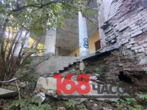 Обрушенные лестница и кирпичная стена у заброшенной колоннады, заросшей деревьями и кустарником