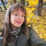 Молодая женщина делает селфи в осеннем парке среди деревьев с жёлтой листвой