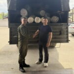 Двое мужчин пожимают руки у грузовика с рулонами матрасов