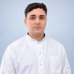 Портрет молодого мужчины в белом медицинском халате на светло-голубом фоне