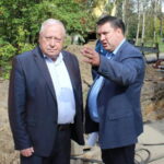Двое мужчин в деловых костюмах беседуют у траншеи и оборудования на участке ремонтных работ
