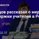 мужчина в костюме за столом с микрофоном и стопкой книг на фоне фиолетового баннера; поверх кадра крупный белый заголовок