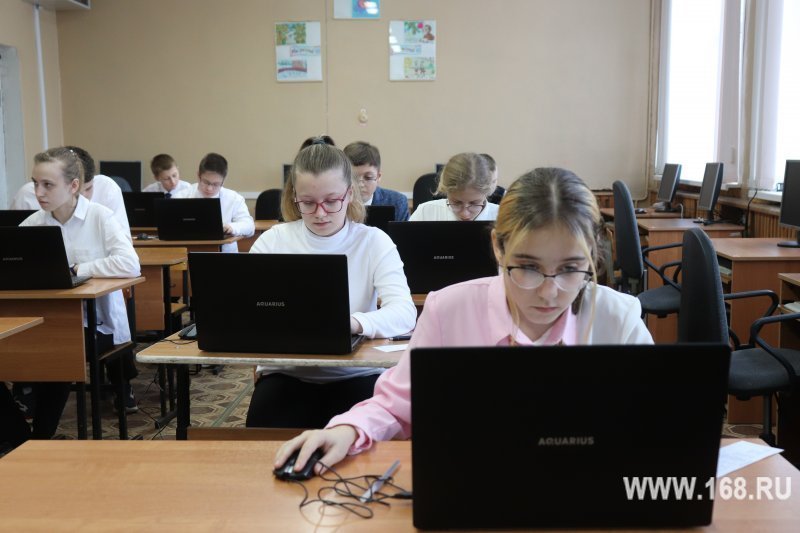 Школьники в компьютерном классе за ноутбуками, несколько рядов учеников за партами