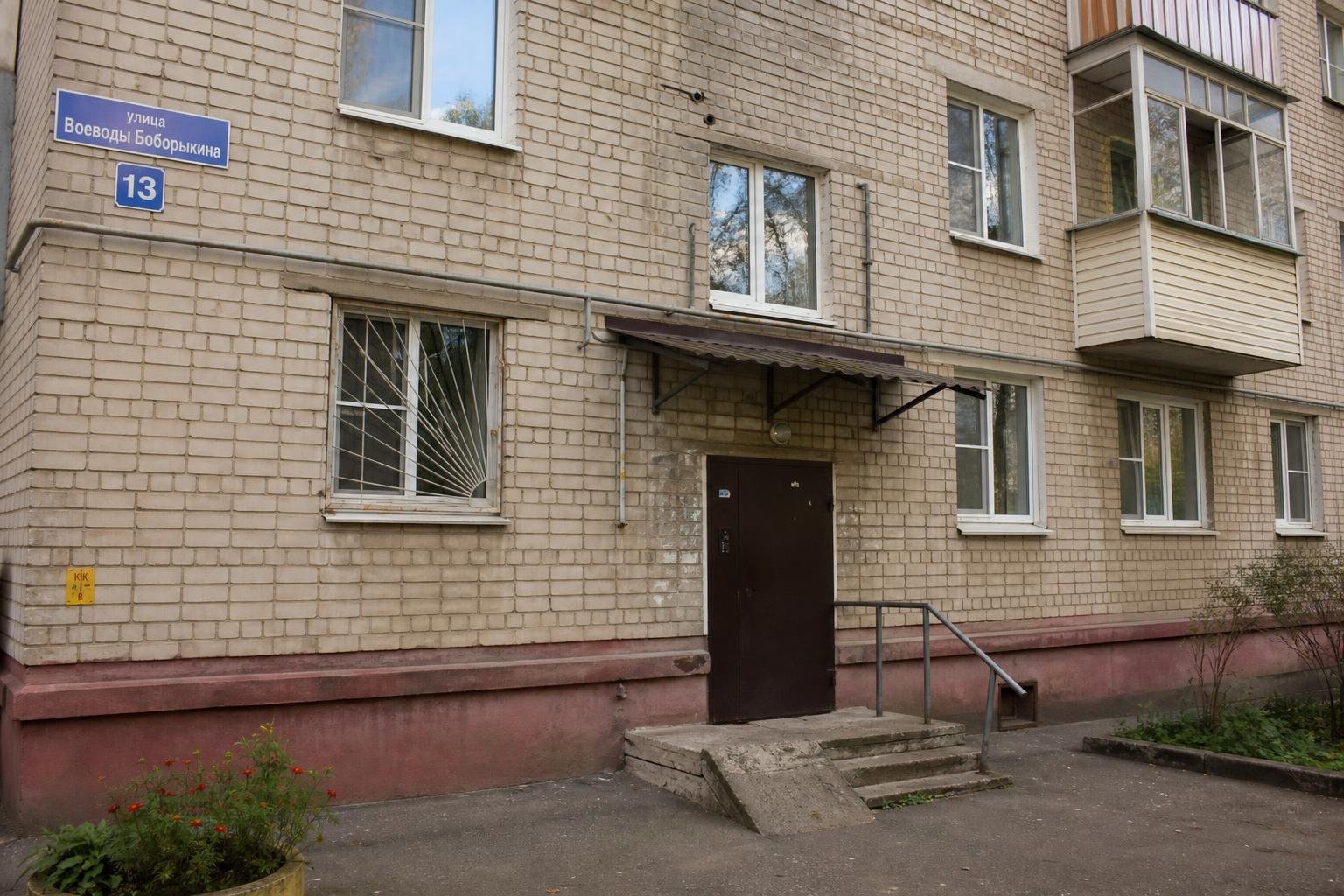 Фасад жилого многоквартирного дома с подъездом, табличкой «улица Воеводы Боборыкина» и номером дома 13.