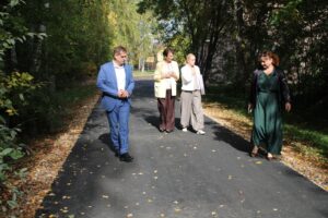 Мужчина и три женщины идут по асфальтированной дорожке среди деревьев