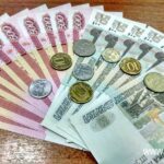 Разложенные на столе российские банкноты номиналом 500 и 50 рублей и разнокалиберные монеты (наличные рубли).