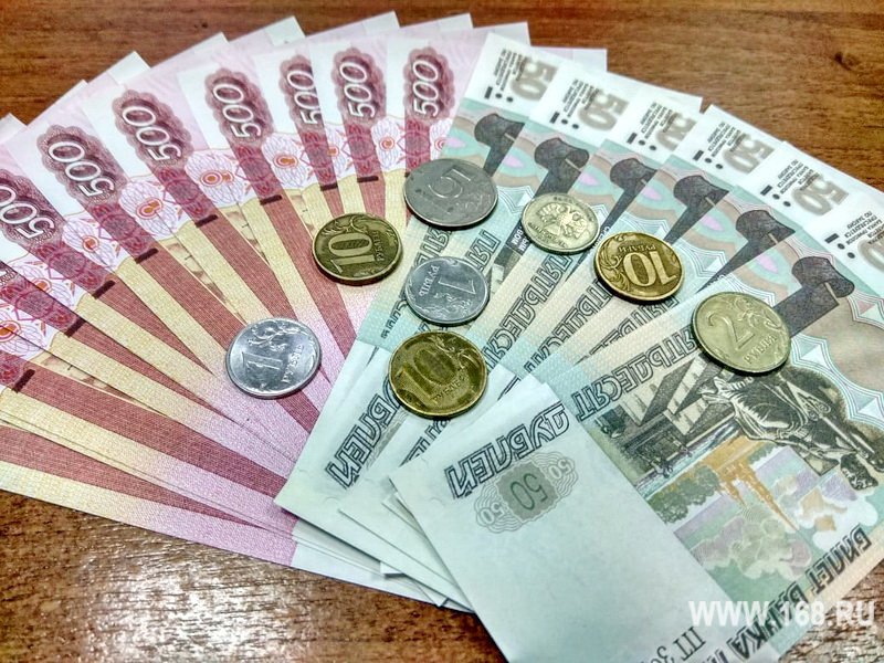 Разложенные на столе российские банкноты номиналом 500 и 50 рублей и разнокалиберные монеты (наличные рубли).