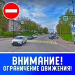 Улица с пешеходным переходом, припаркованными автомобилями и большим синим баннером «ВНИМАНИЕ! ОГРАНИЧЕНИЕ ДВИЖЕНИЯ!», сверху добавлен знак «въезд запрещён».