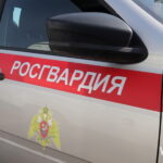 Крупный план борта служебного автомобиля Росгвардии с красной полосой и ведомственной эмблемой