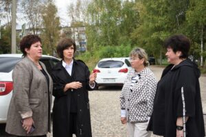 Четыре женщины беседуют на парковке рядом с автомобилями и деревьями