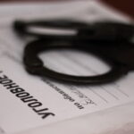 Наручники лежат на раскрытом документе с надписью «Уголовное дело»