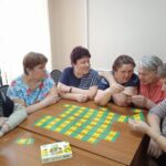 Женщины за столом играют в настольную игру
