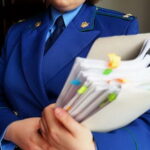 Сотрудник в синем форменном кителе держит толстую папку с документами и цветными закладками