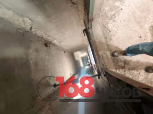 Вид сверху в глубокую шахту внутри заброшенного здания; у края стоят ноги человека