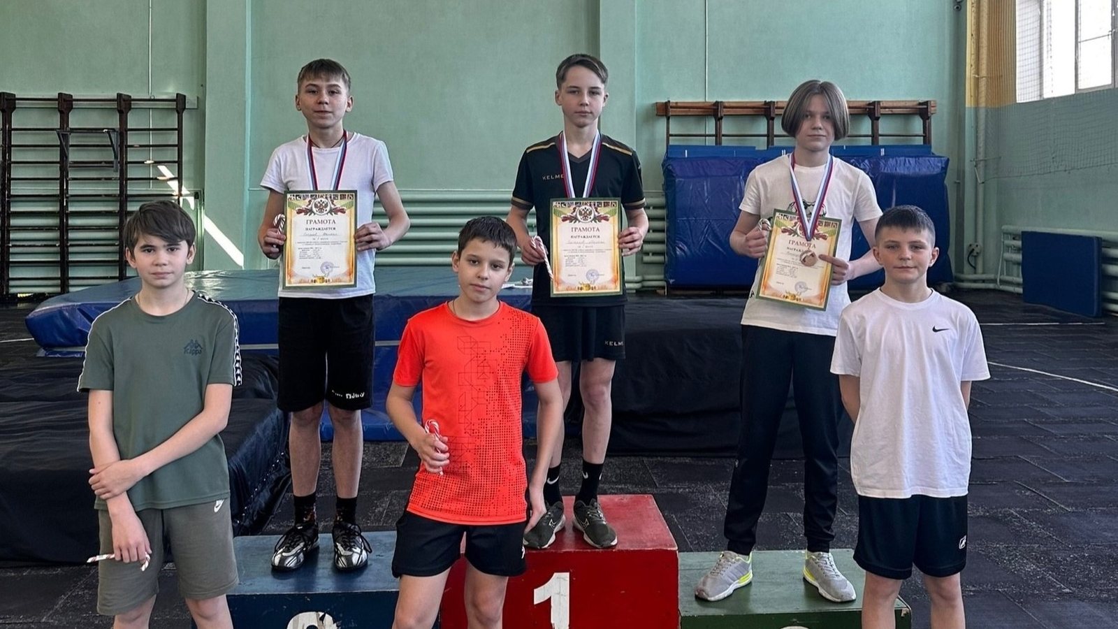 Юные легкоатлеты с медалями и грамотами в спортивном зале