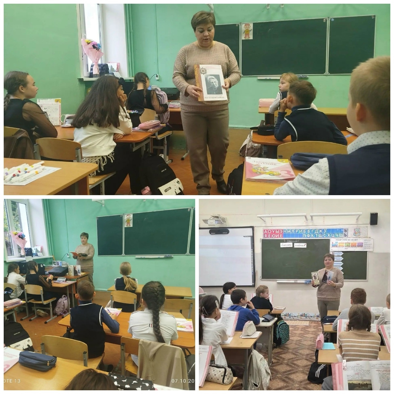 взрослая женщина стоит перед школьной доской и держит книгу с портретом; дети сидят за партами в классной комнате, на столах учебники и тетради