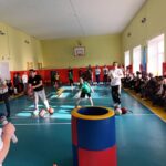 Внутренний школьный спортивный зал: папы и дети участвуют в эстафетах, снаряды и сидящие зрители вдоль стены