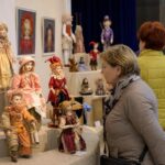 Посетители осматривают экспозицию авторских кукол в выставном зале