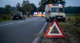 Аварийный треугольник на обочине; на фоне скорая помощь и автомобили с включёнными мигалками на дороге