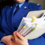 Человек в синей форменной одежде держит папку с большим объёмом документов.