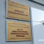 Стена у входа с двумя металлическими табличками: «Филиал поликлиники №1» и «Центр амбулаторной онкологической помощи», на табличках виден адрес «ул. Текстильная, д.6»; водяной знак www.168.ru.