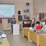 Конференц-зал: докладчик у трибуны, на экране проектора заголовок конференции, за столами сидят участники и зрители