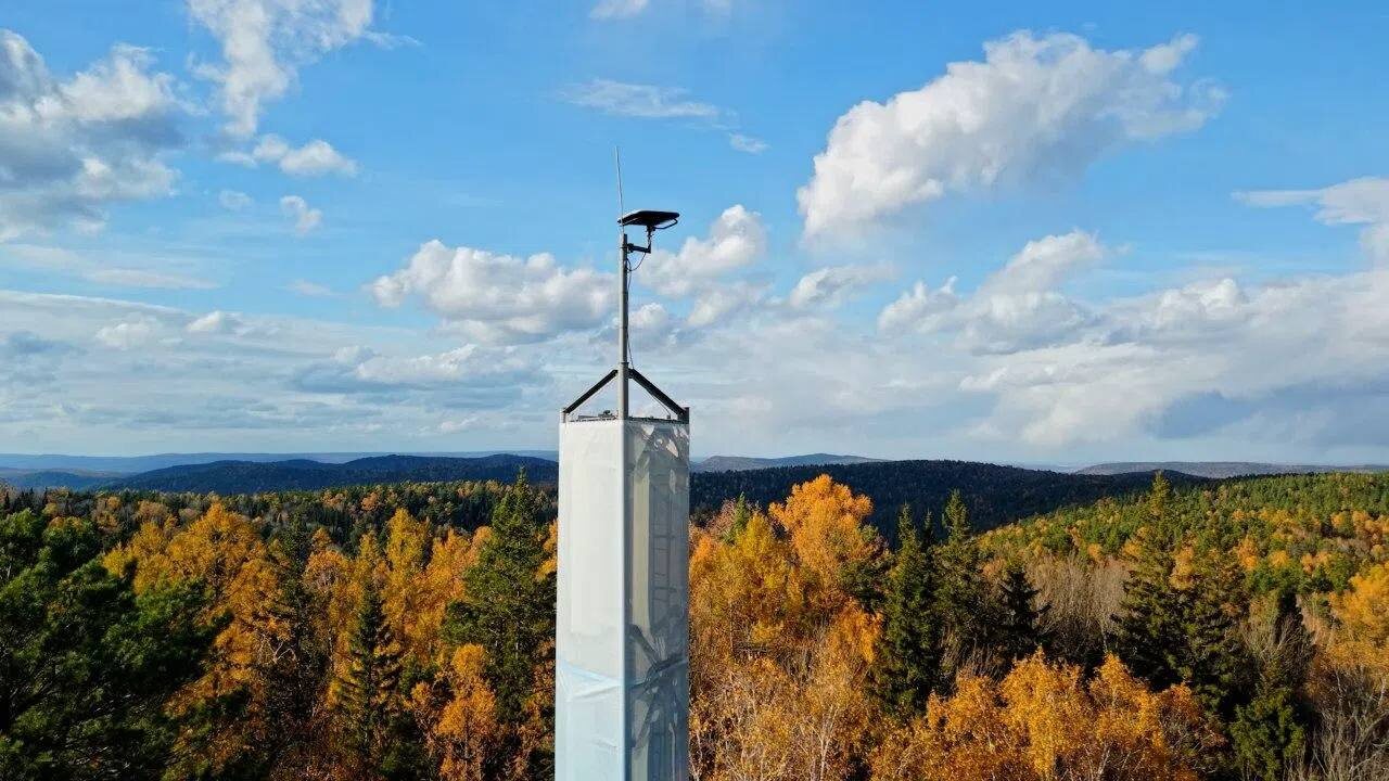 Связное оборудование на башне на фоне осеннего леса и голубого неба