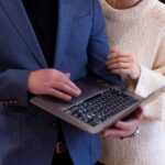 Два человека с ноутбуком и 5G-роутером на столе в офисе