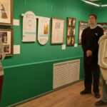 Группа школьников в выставочном зале музея у витрины и картин на стене