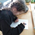 ученица за партой заполняет лист с заданиями