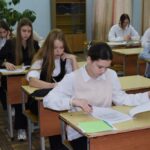 Ученики в школьном классе за партами выполняют задания на бумаге.