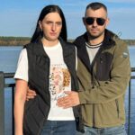Молодая пара стоит на набережной на фоне воды и неба
