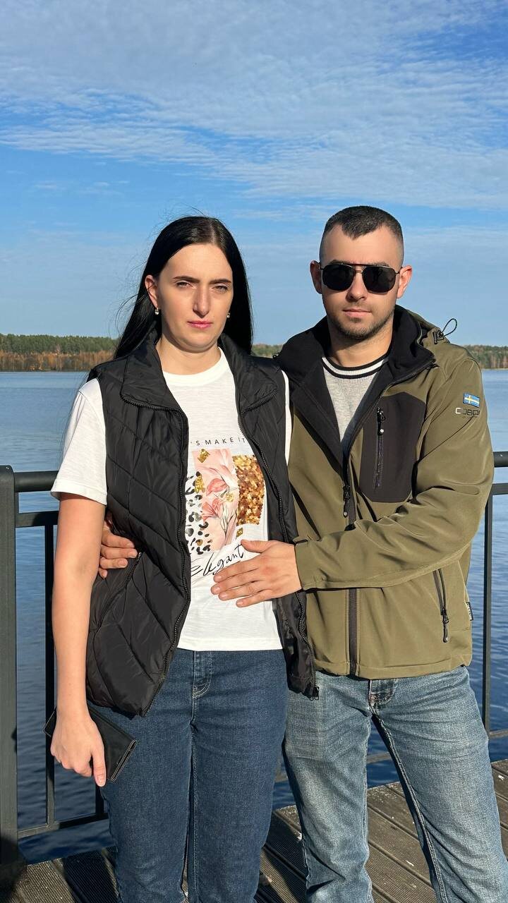 Молодая пара стоит на набережной на фоне воды и неба