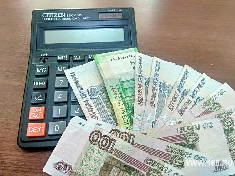 Калькулятор и разложенные купюры российских рублей на деревянном столе