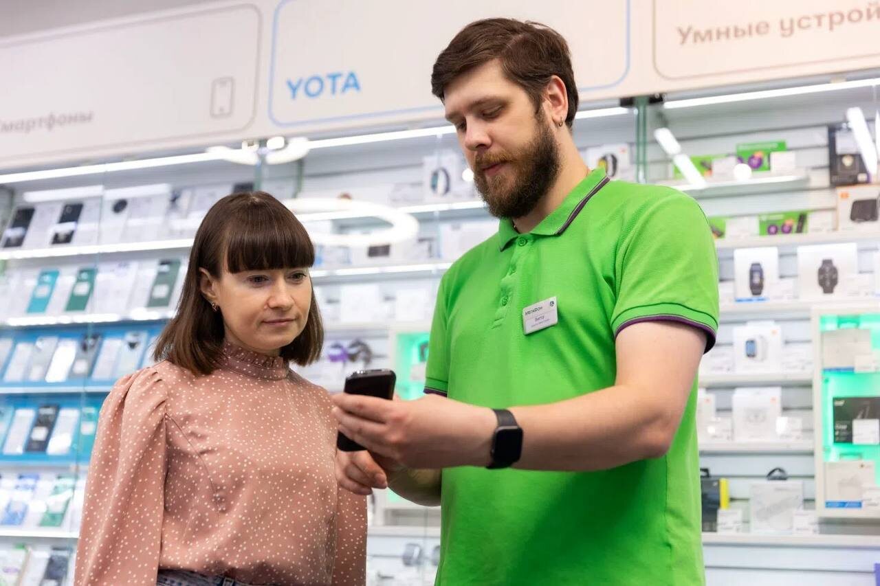 Продавец консультирует покупательницу по функционалу смартфона в салоне связи