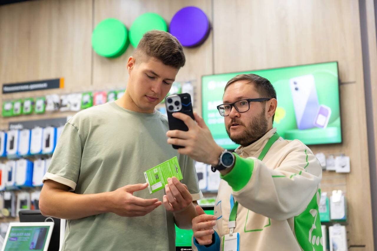 Консультант помогает покупателю выбрать смартфон в магазине мобильной связи