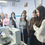 Группа старшеклассниц у швейной машины в цехе (несколько катушек нити, рабочее оборудование марки JACK)