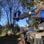 бригада на автовышке кронирует/спиливает дерево у жилых домов