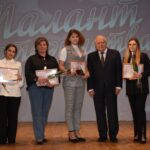 На сцене несколько человек держат дипломы и розы на фоне баннера с надписью «Талант материнства».