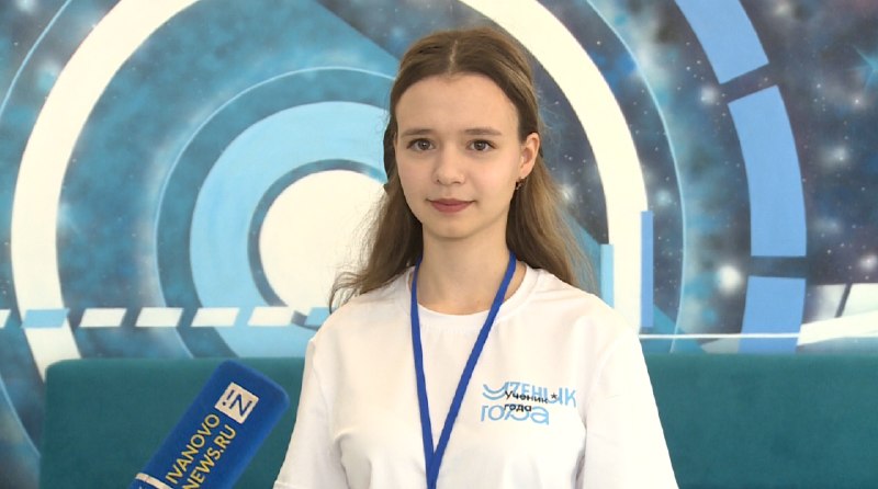 Подросток в белой футболке с логотипом «Ученик года» и синий лента-бейдж на шее, на фоне декоративной графики зала; рядом микрофон с надписью «IVANOVONEWS.RU».