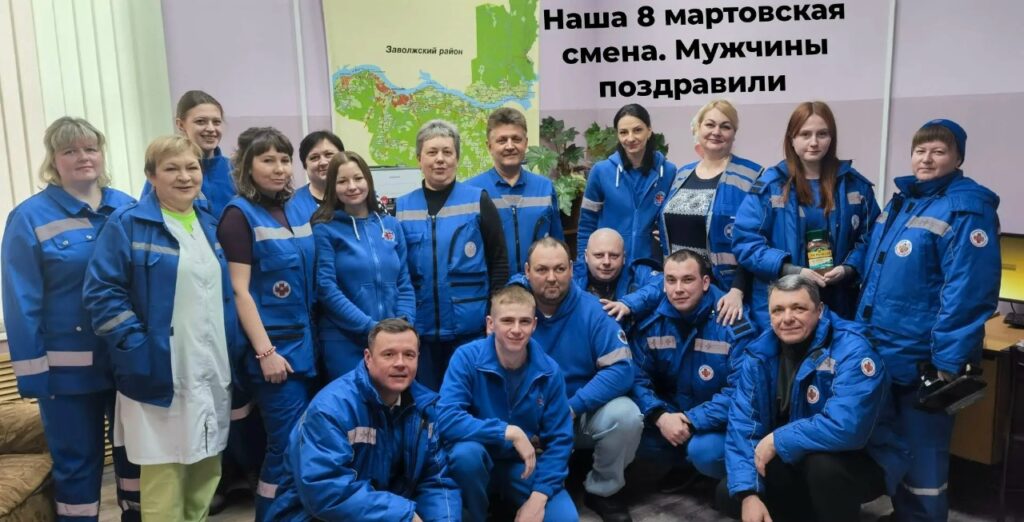 Группа сотрудников скорой помощи в синей форменной одежде позирует в помещении