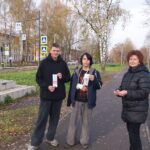 три человека на тротуаре держат длинные бумажные закладки (карманные памятки)