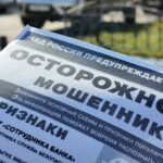 лоток/листовка с заголовком «ОСТОРОЖНО! МОШЕННИКИ!» и логотипом/надписью «МВД РОССИИ» на фоне улицы