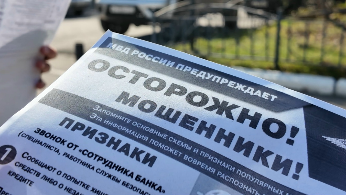 лоток/листовка с заголовком «ОСТОРОЖНО! МОШЕННИКИ!» и логотипом/надписью «МВД РОССИИ» на фоне улицы